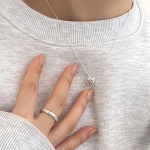 Detail of minimalist 925 sterling silver heart pendant necklace worn on a gray hoodie