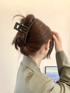 Matte black geometric hair claw clip shown in a stylish updo on a female model