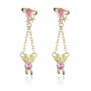 Macro detail of gold-plated bear earrings with pink heart gemstones and dangling chains