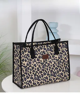 Detail shot of the large leopard print tote bag with black handles on a white table