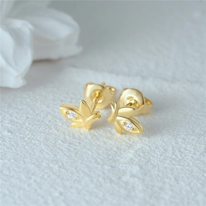 Macro shot of gold butterfly stud earring with sparkling round zircon on white texture