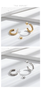 Detail view of gold and silver C-shaped titanium steel earrings with cubic zirconia stones