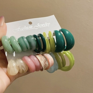 Détail de boucles d'oreilles créoles en acrylique multicolores sur carte de présentation