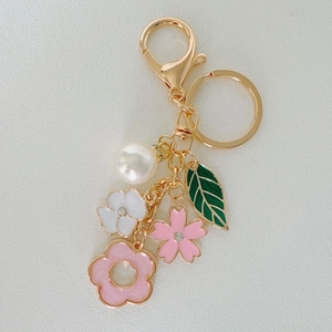 Detail of leaf and flower keychain with rhinestones, white pearls and pink floral charms