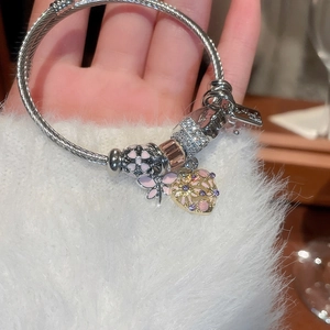Detailed close-up of a beaded charm bracelet with pink enamel flower and heart pendants
