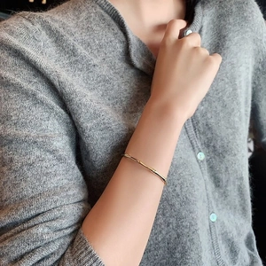 Detailed close-up of a golden bamboo-style stainless steel bangle worn on a model's wrist