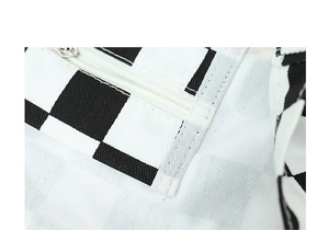 Close-up of black and white checkerboard canvas fabric with a white zipper closure