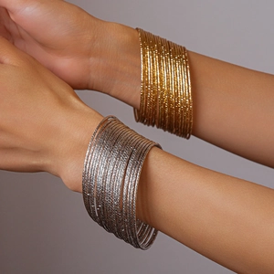 Dettaglio di bracciali multistrato oro e argento con trama diamantata sul polso femminile