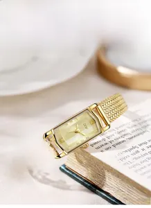 Detail of GEDI golden watch with octagonal mirror and mesh strap on a book