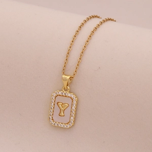 Gros plan du pendentif carré en or avec nacre blanche et lettre Y sertie de cristaux