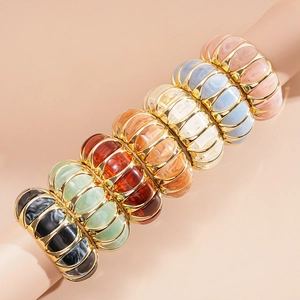 Detail of colorful resin and metal striped bangles on a cylindrical display stand