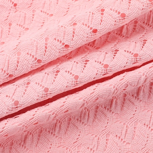 Détail de la dentelle rose montrant les motifs floraux délicats et les ajourages