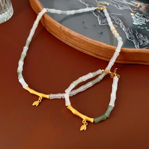 Detailed close-up of bamboo-style bead necklace and bracelet set with gold leaf charms