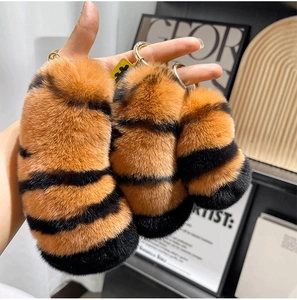 Detailed view of three striped tiger tail plush keychains in varied sizes with gold rings