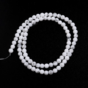 Macro shot of natural white turquoise round beads with grey marble texture on black background