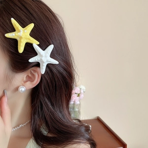 Detail view of stylish starfish hair clips in yellow and white on female hair