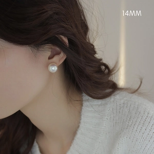 Detailed close-up of 14mm large round white pearl stud earring worn on model's ear