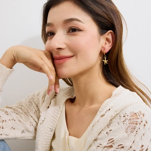 Elegant gold starfish stud earrings worn by a smiling woman with a polished finish