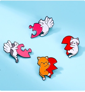 Detailed close-up of four enamel cat pins with wings and puzzle pieces on blue backdrop