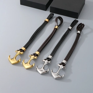 Close-up of gold and silver anchor charms on woven leather straps in a group