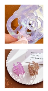 Macro shot of purple hollow camellia acetate hair claw and small transparent hair clips