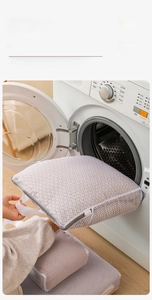 Detail of placing a honeycomb mesh laundry bag with gray handle into a washing machine