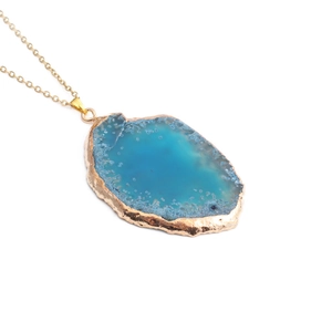Vue détaillée du pendentif tranche d'agate bleue avec bordure dorée et chaîne en or