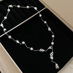 Detail of silver chain necklace with pearls and abstract face beads on black velvet