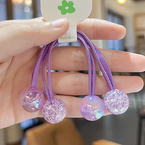 Detailed view of three purple elastic hair ties with glitter and clear bead ornaments