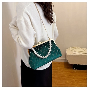 Detail of green velvet evening bag featuring quilted pattern with pearls and chain