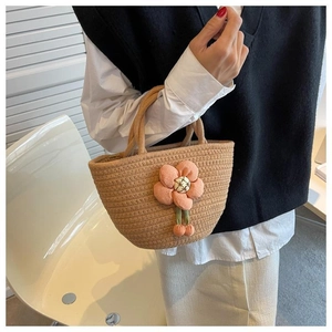 Detail of hand-woven straw bag featuring a pink fabric flower and cherry accents