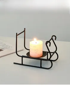 Detail shot of a black metal sled candle holder with a white pillar candle on a table