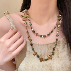 Close-up of a vintage double-layer beaded necklace featuring green and brown shell chips