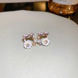 Floral pearl earrings with purple heart crystals and gold base on a ceramic tray