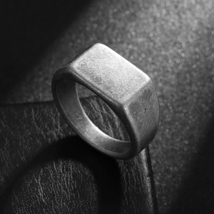 Macro shot of minimalist rectangular signet ring with vintage matte finish on black leather