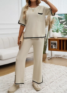 Détail d'un ensemble en tricot beige avec finitions noires sur le haut et le pantalon large