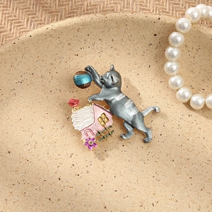 Close-up of a vintage rhinestone cat and house brooch displayed with elegant pearls