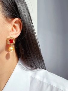Gros plan d'une boucle d'oreille en or vintage avec une gemme rouge et une perle champagne