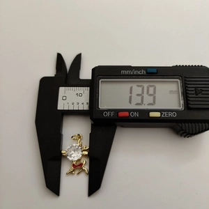 Detailed measurement of the golden reindeer pendant showing a width of 13.9mm on a caliper