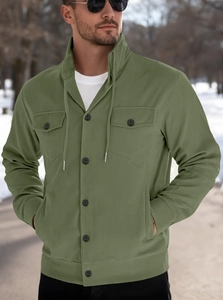 Detail of green corduroy jacket fabric showing flap pockets and button closure in the snow