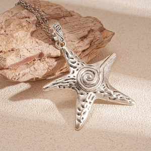 Vintage metallic starfish pendant necklace with spiral texture on natural stone background