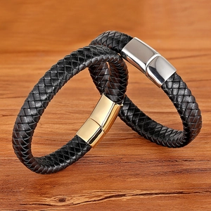Braided leather bracelets with silver and gold metal clasps on a rustic wood background