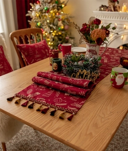 Detail of red Christmas table runner with golden bell jacquard patterns and tassels