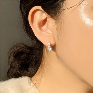 Close-up of a 925 sterling silver hoop earring with paved zircons on a model's ear