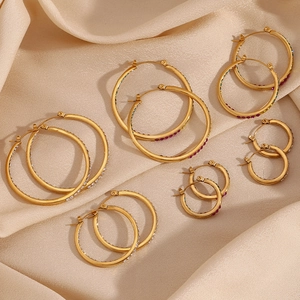 Detailed view of gold stainless steel hoop earrings with colorful zircon inlay on satin
