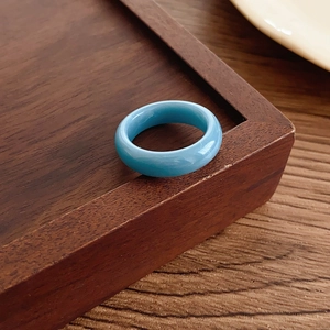 Macro shot of minimalist translucent light blue resin ring on a vintage wooden tray