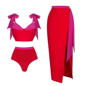 Three-piece red swimwear set detail showing pink bow straps and matching sarong wrap