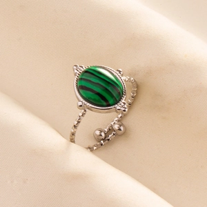 Detail of adjustable silver ring with oval green malachite stone on soft fabric
