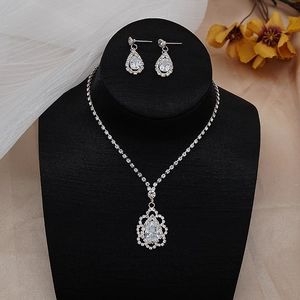 Macro detail of bridal jewelry set with pear-cut zircon halo necklace and teardrop earrings