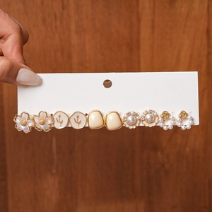 Detail of 6-pair gold earring set with white enamel flowers and pearls on display card